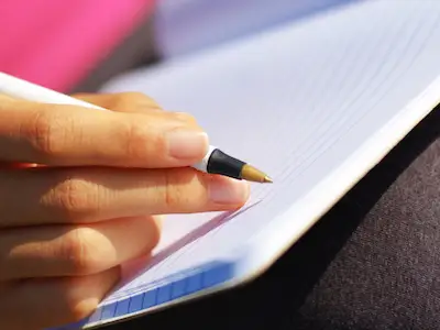 女性手握着笔即将写在日记里。