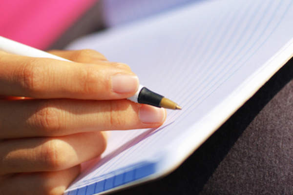 女手拿着钢笔关于日记写。