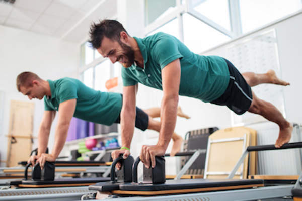 两名男子在健身房做普拉提。