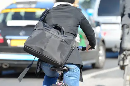 沉重的手提电脑包在女性通勤者骑自行车上班。