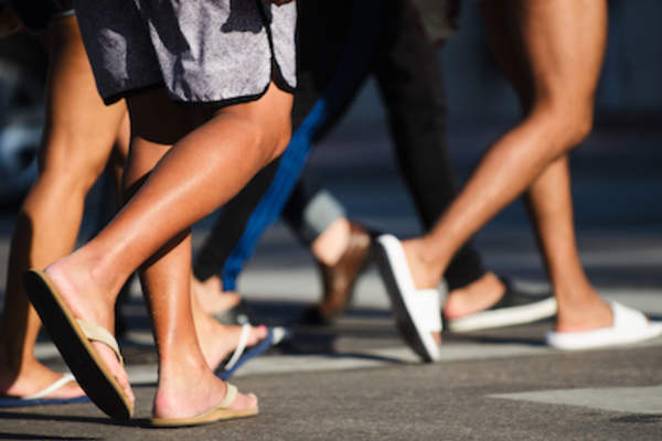 穿人字拖和凉鞋过马路的人。