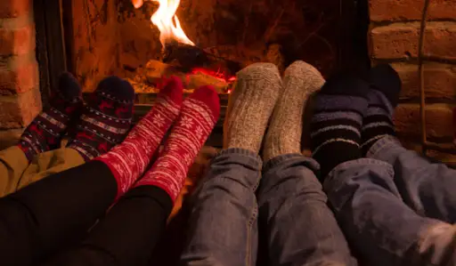 脚穿着暖和的袜子在壁炉前