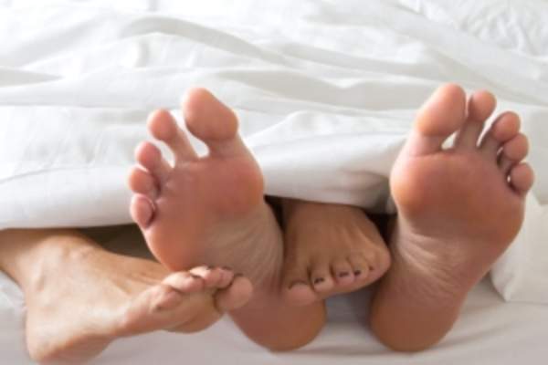 一对夫妇的脚从床单下伸出来
