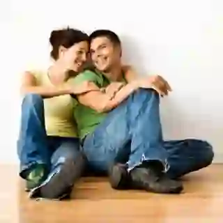 Couple sitting against a wall, smiling