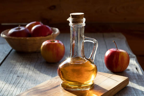 A bottle of apple cider vinegar with apples.