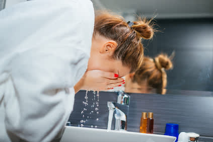 女人在浴室的水池里洗脸。
