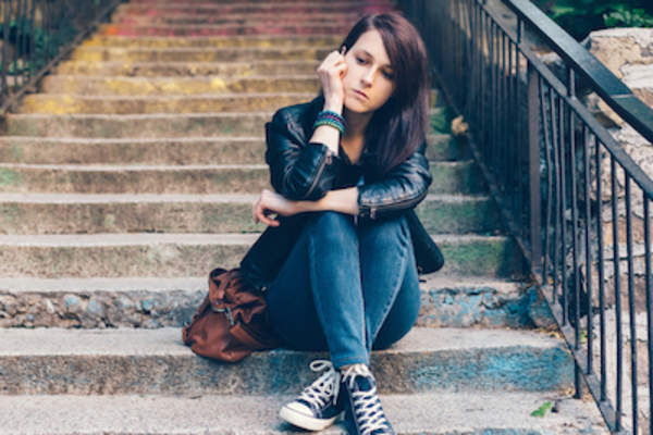 沮丧的年轻女子坐在楼梯上。