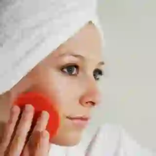 Woman keeping her skin looking good using exfoliating pad. 