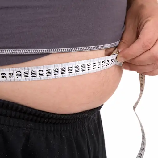 Overweight man measuring stomach.