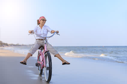 在海滩上骑巡洋舰自行车的中年妇女。