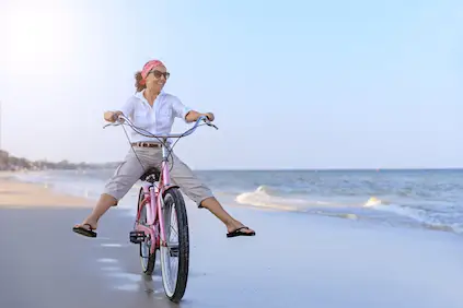 中部变老的妇女骑马巡洋舰自行车在海滩。