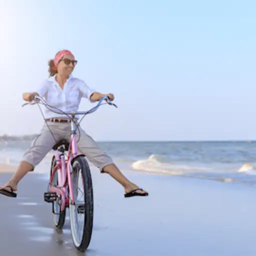 中部变老的妇女骑马巡洋舰自行车在海滩。