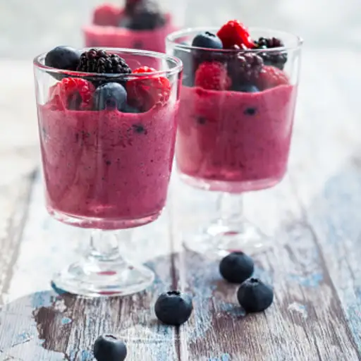 Small cups of berry smoothie topped with fresh berries.