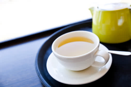 一杯绿茶放在托盘上，有茶碟和勺子。