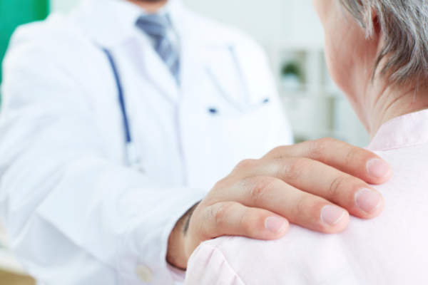 医生的手放在病人的肩上。