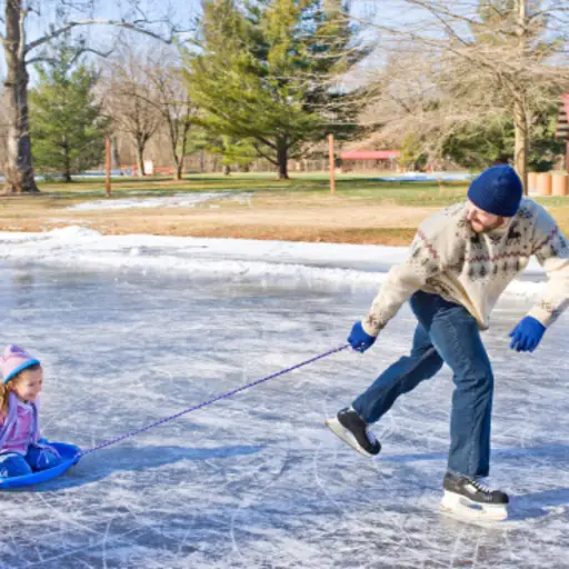 穿着冰鞋的男人拉着小女孩在雪橇上。