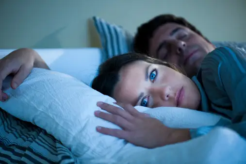 女人在床上睡得很醒，紧挨着丈夫。