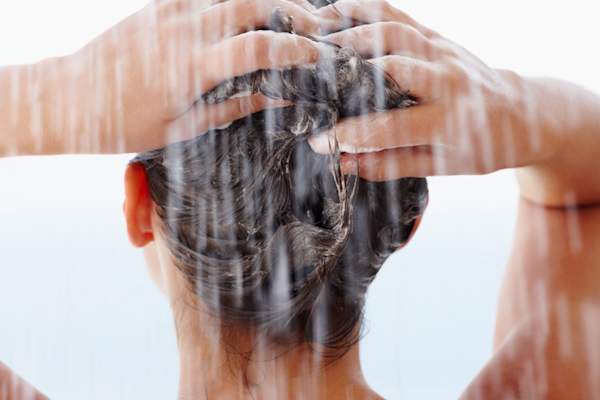 妇洗她的头发在淋浴