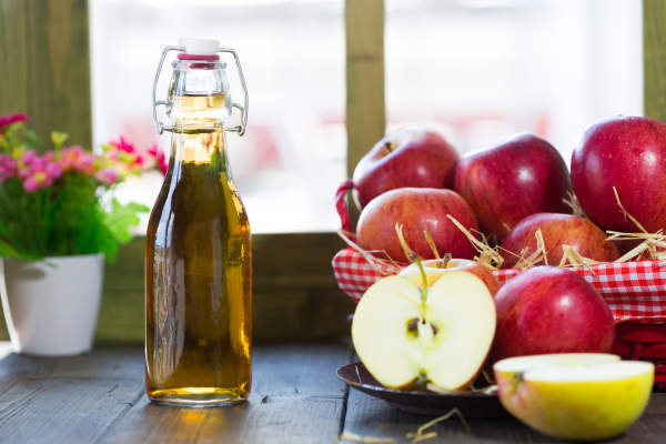一瓶苹果醋和新鲜的苹果。