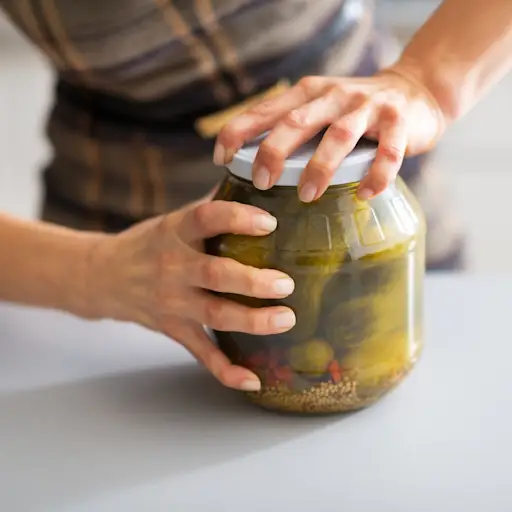 Woman trying to open a pickle jar.