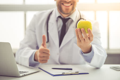 医生微笑拿着一个苹果。