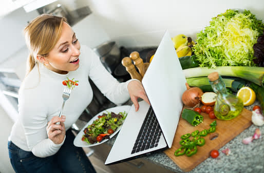 女人在笔记本电脑上吃沙拉。