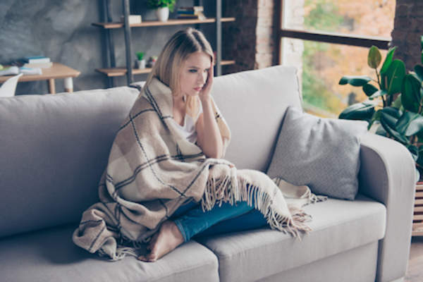 女人在沙发上,裹着扔,在全身不适。