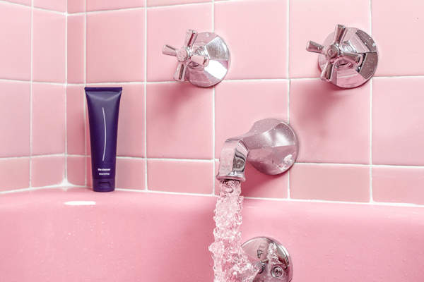 水从粉色瓷砖浴缸的水龙头流出