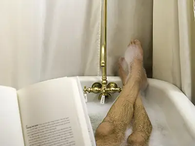 读和放松在浴缸里的人。