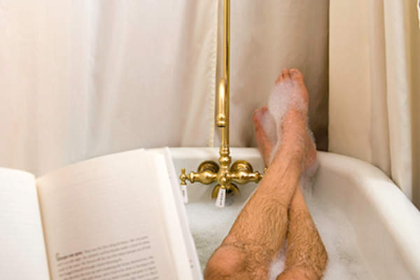 男人在浴缸里看书和放松。