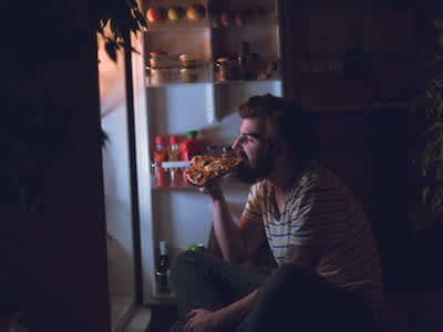 男人在午夜吃零食的冰箱。