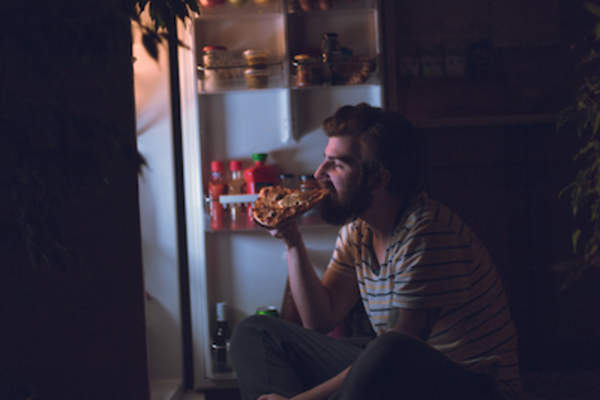 男人在午夜吃零食的冰箱。
