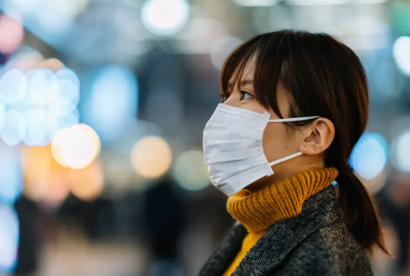 年轻的亚洲女子戴着防细菌的口罩。