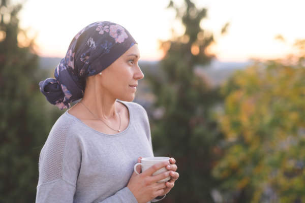 女子与癌症戴头巾，喝茶，站在外面