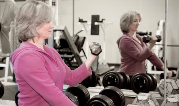 妇女在健身房锻炼，在镜子前。