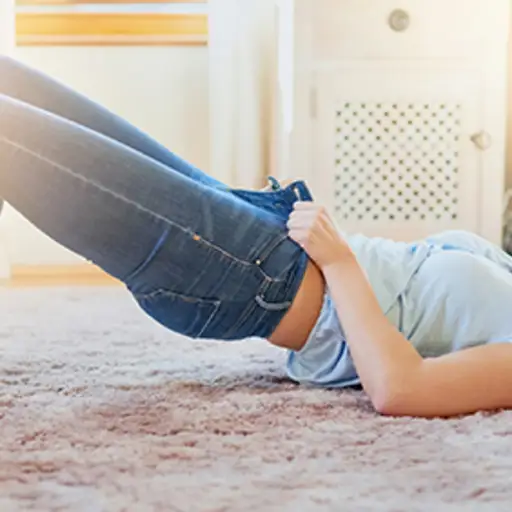 努力挣扎的妇女穿上一条紧身牛仔裤。