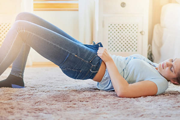 一个女人挣扎着穿上一条紧身牛仔裤。