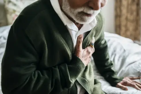 Older man grabbing chest in pain.