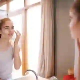 young woman putting on face cream