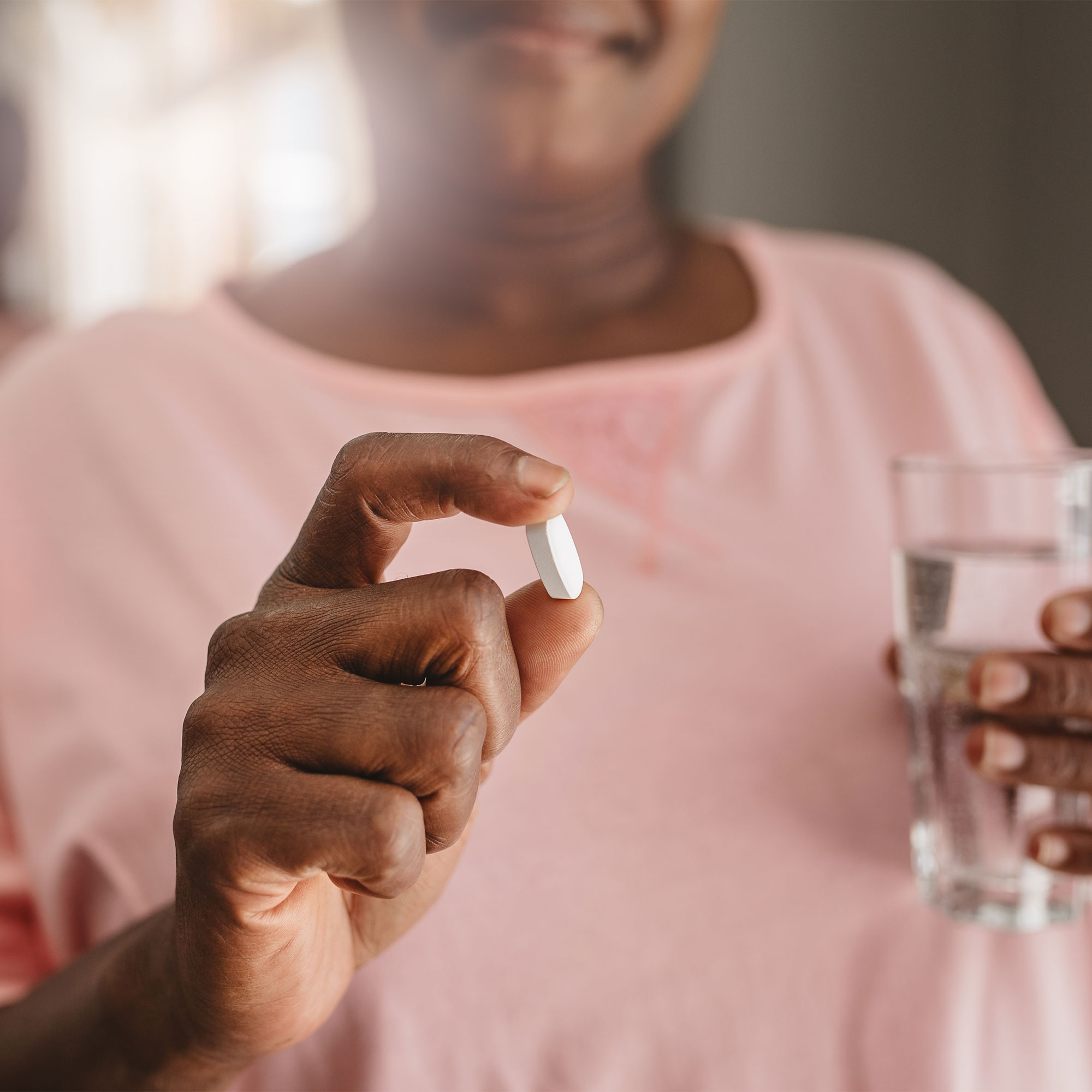 女人拿着一杯药和一杯水