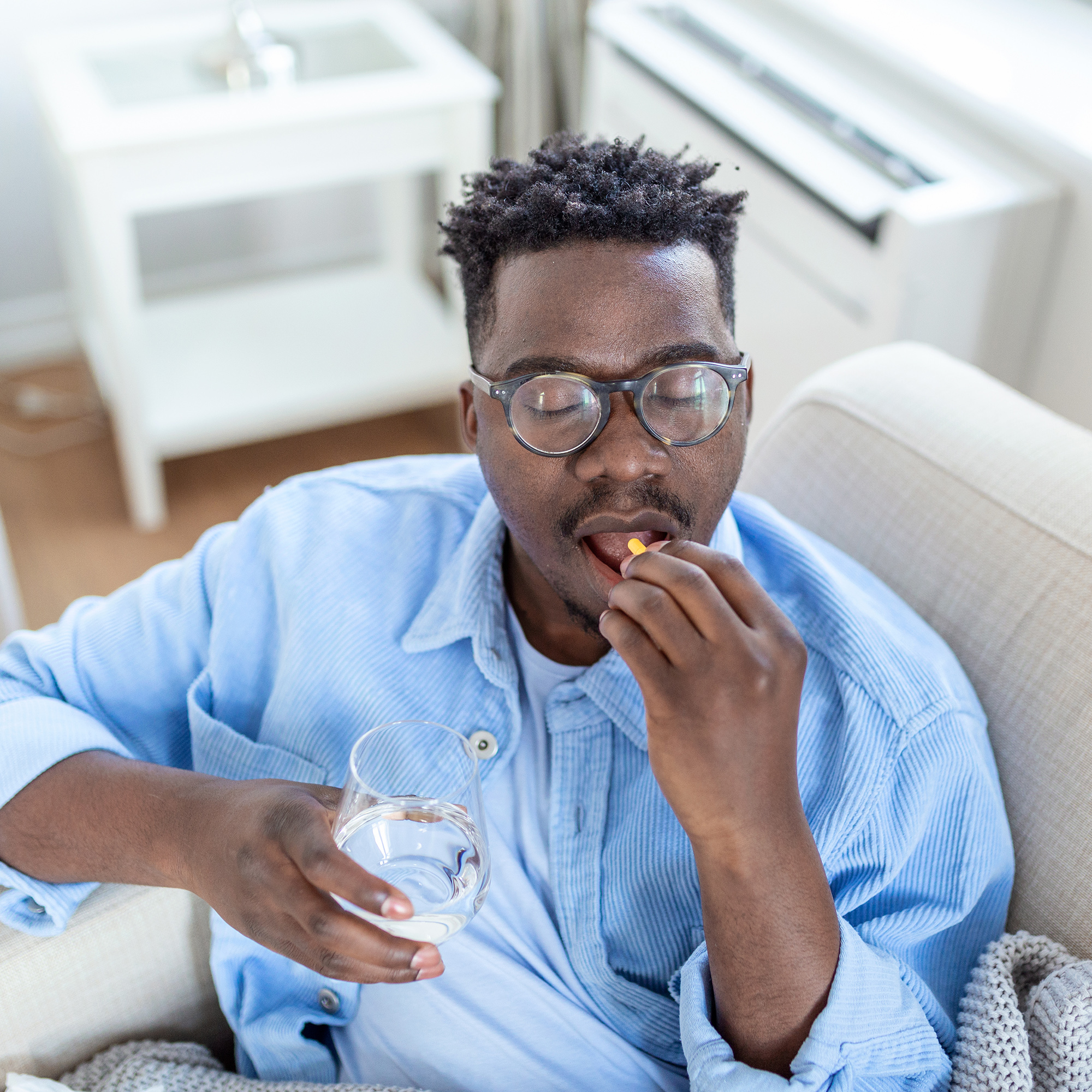 一个男人拿着一杯水吃着药