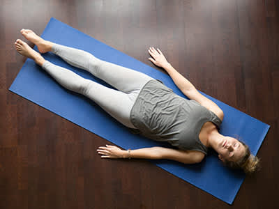 在瑜伽垫上做尸体姿势的女人。