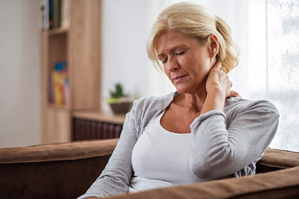 疲惫的女人在家里的沙发上摩挲着自己的脖子。