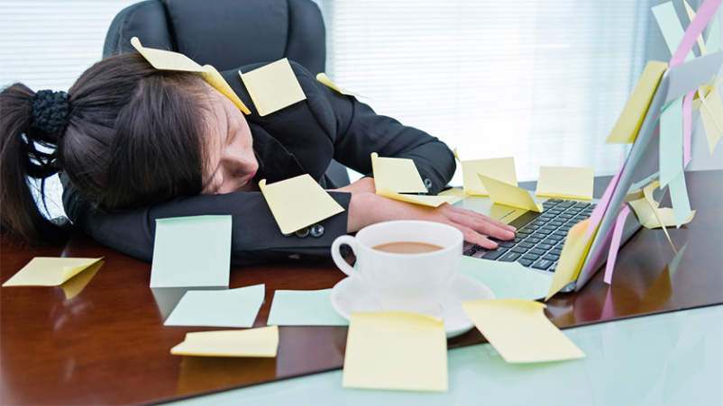 压力大的女人睡在笔记本电脑上覆盖着笔记。