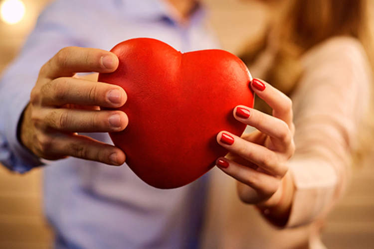 一对情侣抱着一颗红心相拥。