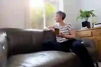 一个女人拿着手机,看着家里的窗户
