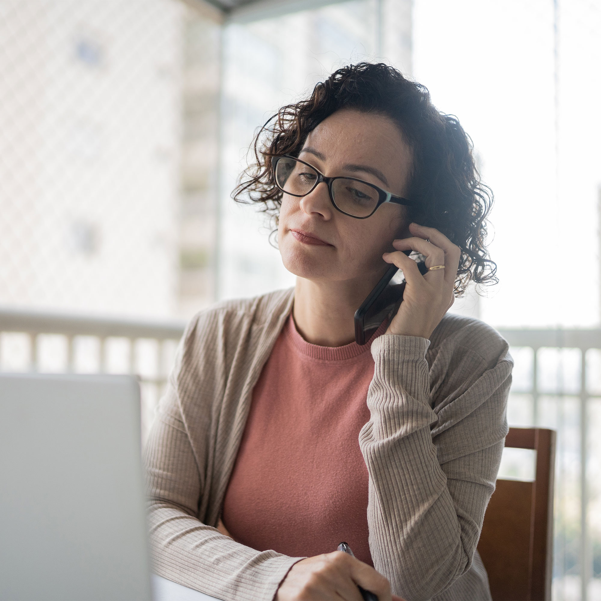 一个女人坐在笔记本电脑前讲电话