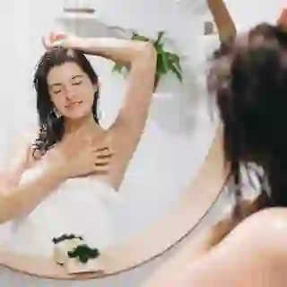 woman looking in mirror touching armpit