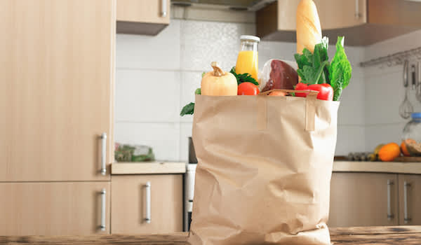购物袋里的食物放在厨房柜台上，随时准备整理和放好。