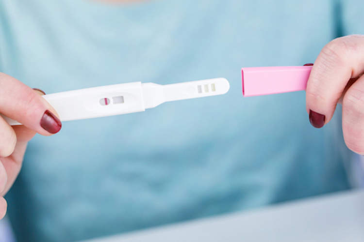 年轻女子拿着她的手妊娠试验